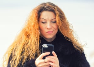 Person ser nølende ned på telefonen
